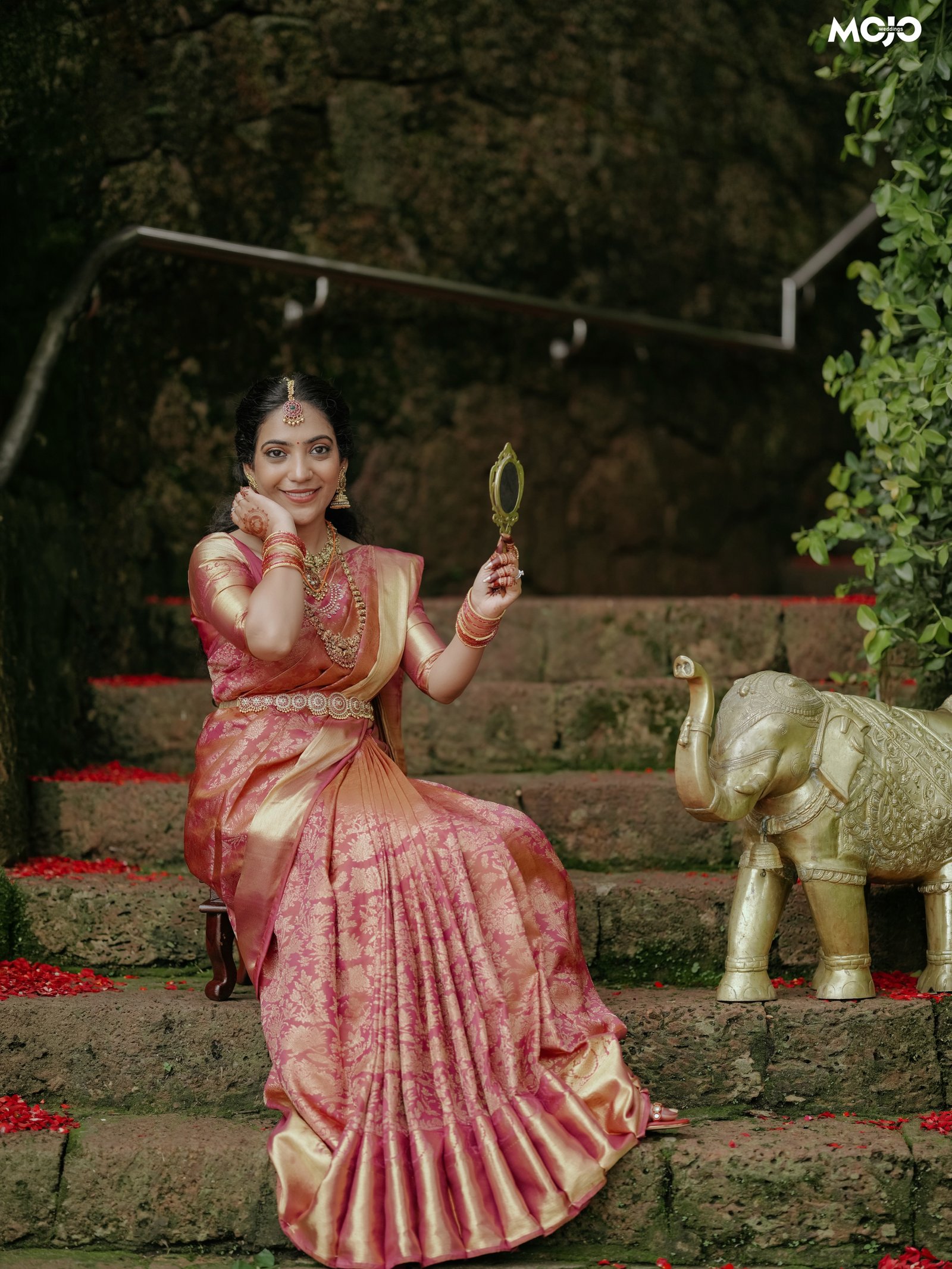 A bride in a traditional sari holding a hand mirror