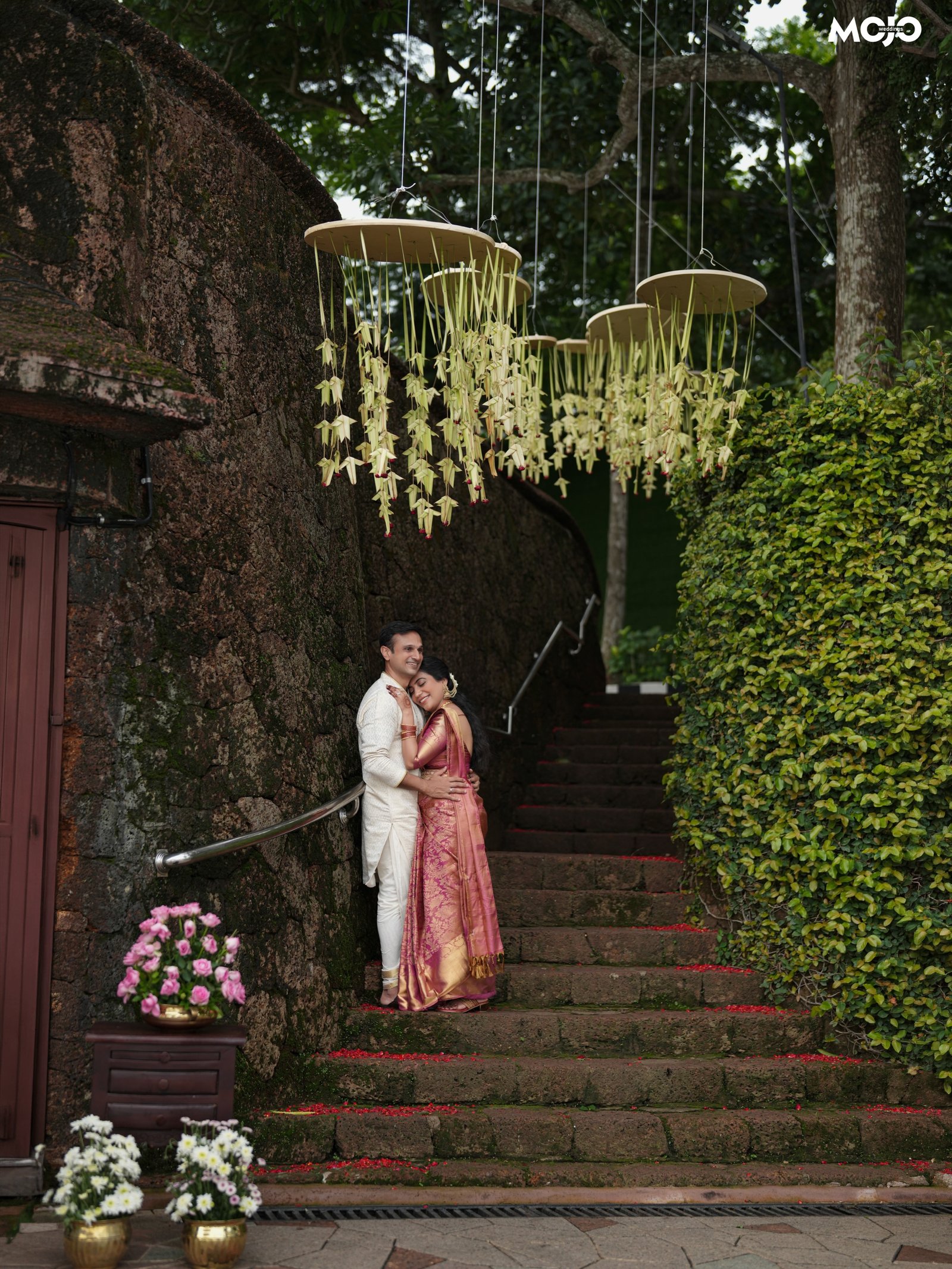 A newlywed couple embracing beneath floral decorations